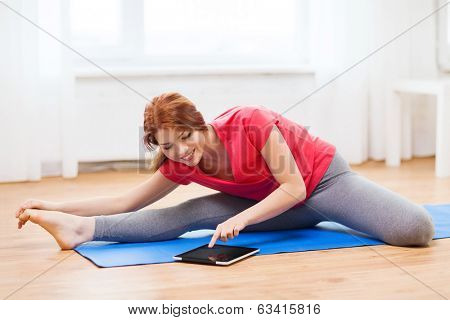 fitness, home, technology and diet concept - smiling teenage girl streching on floor with tablet pc computer at home