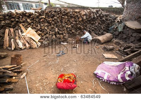 KATHMANDU, NEPAL - DEC 19, 2013: Unidentified man sorts wood for cremation rites in Bhasmeshvar Ghat at Pashupatinath temple in Kathmandu. 