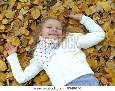 Petite fille couché sur les feuilles d'automne