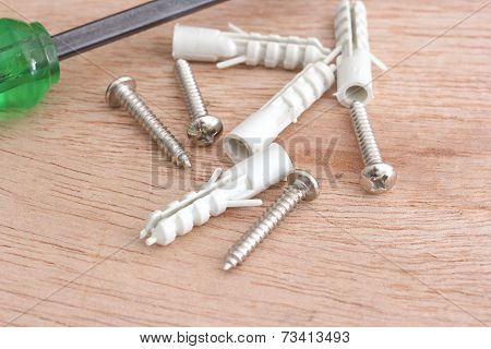 Screws And Plastic Anchor On The Wooden Background