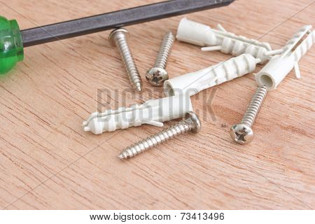 Screws And Plastic Anchor On The Wooden Background