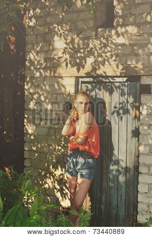 portrait photo of sad beautiful girl standing near brick wall in shadows