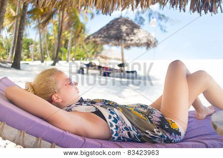 Woman sunbathing on tropical beach.