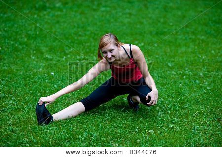 Pierna de stretshes linda chica joven en hierba verde