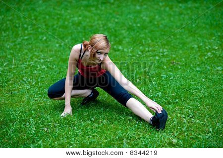 Pierna de stretshes linda chica joven en hierba verde