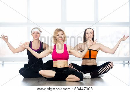 Group Of Three Females Practice Yoga In Class