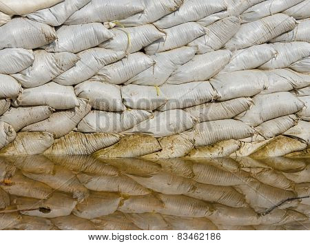 White Sandbags For Flood Defense And It's Reflection Brown Water