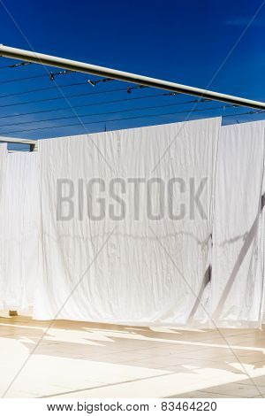 White Clothes Hanging On The Line Against Blue Sky.