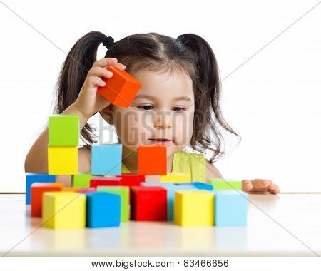 toddler girl builds a tower with colorful blocks