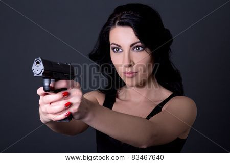 Young Sexy Woman Aiming With Gun Over Grey
