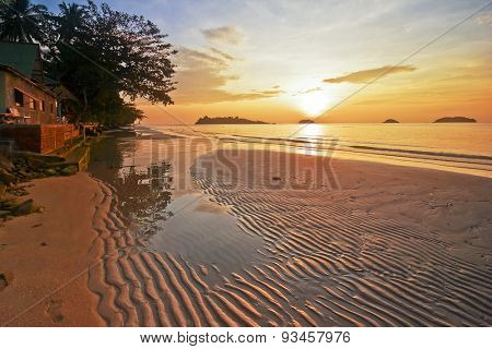 Tropical beach in ebb time on sunset background