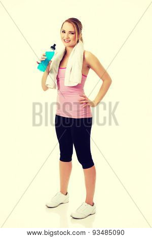 Attractive woman in fitness clothes drinking isotonic drink.