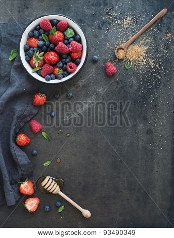 Berry frame with copy space on right. Strawberries, raspberries, blueberries and mint leaves, dark g