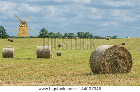 countryside with hilly field and rolls of haystack. Focus is on the nearest roll