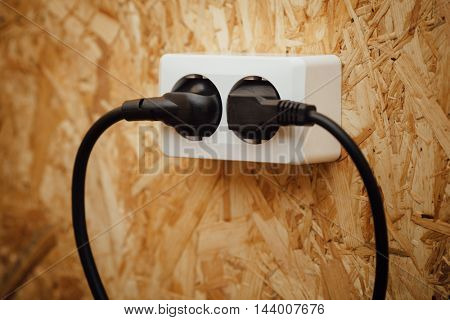 AC power plug and socket, wooden osb wall background