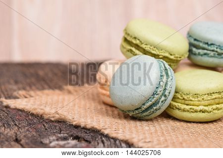 Blue and green macarons on a burlap napkin sitting on rustic barn wood