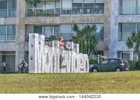 MONTEVIDEO, URUGUAY, DECEMBER - 2015 - Attractive young woman posing for photo at landmark place in which is located the Montevideo letters.