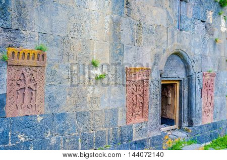 The frontage wall of Hayravank Monastery decorated with the red khachkars built in it Armenia.