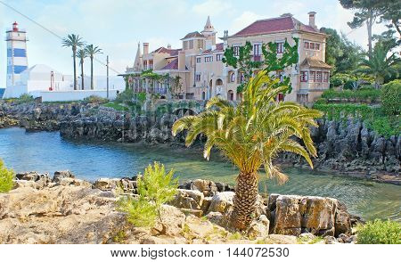 The tiny rocky bay is the nice place to walk and enjoy the historic Villa of Santa Maria and beautiful Santa Marta lighthouse Cascais Portugal.