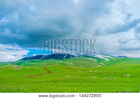 The cloudy weather in highlands with the small snowfields on the mountain top Gegharkunik Province Armenia.