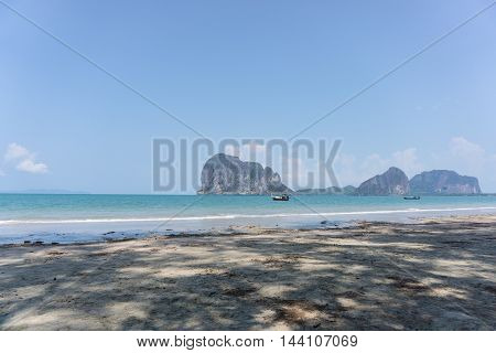 A boat in the beautiful sea and blue sky at Pakmeng beach with tree's shadow in Trang Thailand.