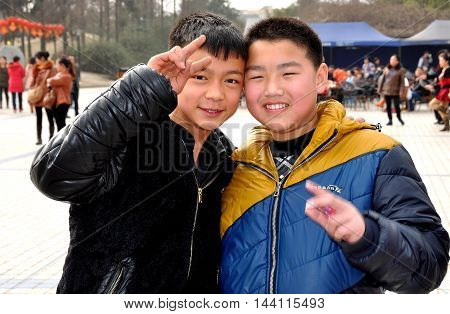 Pengzhou China - February 3 2014: Two friendly Chinese boys flash the V sign in the plaza at Pengzhou Park
