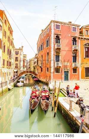 Venice, Italy - May 18, 2016: Cityscape view on canal with gondolas and crowded square dei Frari in Venice.