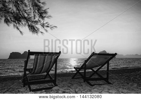double beach chair on sand in b&w filter black and white photo