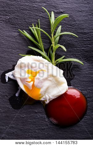 Single Poached Egg On Black Stone With Herb And Ketchup