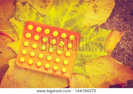 Pill package on leaf. Pack of pills lying on maple leaves. Nature vegetation health medicine concept.
