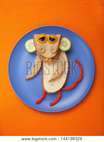 Amusing monkey made of bread cheese and vegetables on plate and fabric