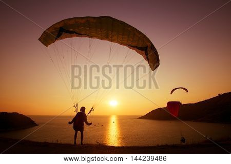 Skydiver preparing to start flying over the bay on background of sunset sky. Phuket island, Thailand