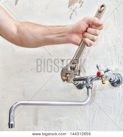 Close-up of plumber hands fixing faucet cartridge using plumbers adjustable wrench spanner.
