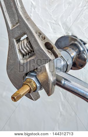 Close-up adjustable spanner plumbers screwing water faucet valve for tap.