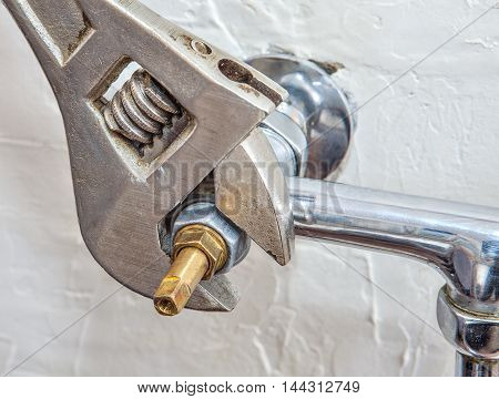 Close-up an adjustable wrench plumbers fixes the valve for water faucet.