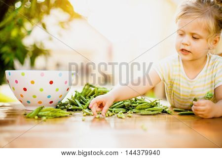 Beautiful girl enjoying outhside and peeling peas off.