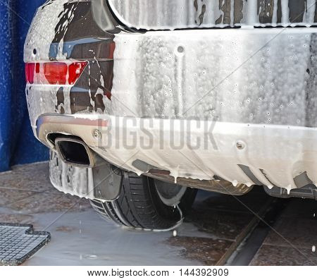 Car fragment in flowing-down soapsuds during washing