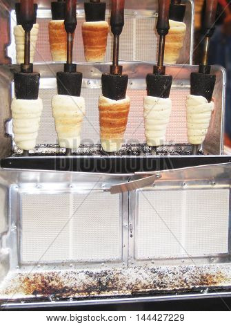 Trdelnik machine with fresh baked traditional Czech cake and sweet pastry made from rolled dough.