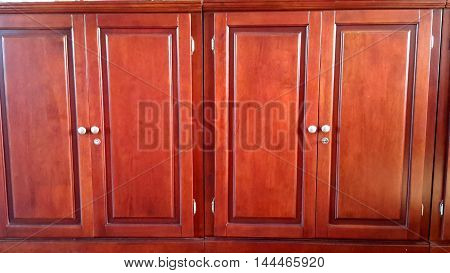 reddish varnished locking wooden storage cabinets with white knobs, recessed panels, Ranot, Thailand