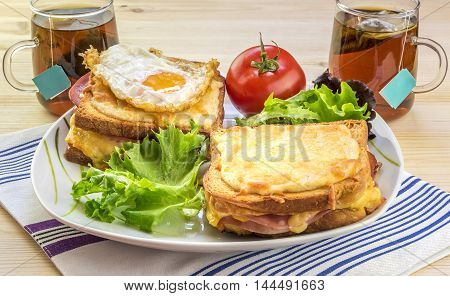 French breakfast for two people - Tasty breakfast for two persons with specific french food croque madame (with egg) and croque monsieur seasoned with fresh salad and tea.