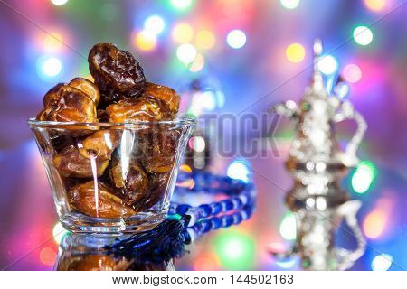 Date fruits in glass tumbler with Muslim prayer beads. Ramadan Eid concept