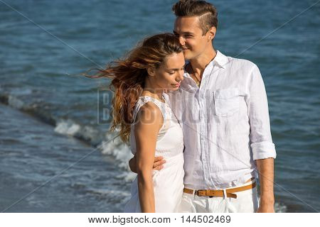 happy couple in love walking on the beach in summer white dress