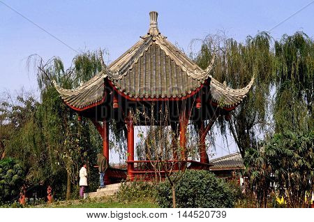 Pixian China - November 3 2009: A hexagonal viewing pavilion with flying eave roofs sits in a small park surrounded by weeping willow trees