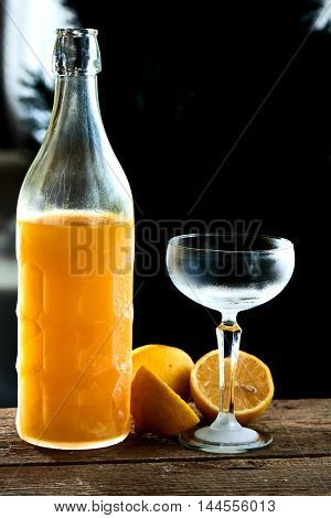 Alcoholic cocktail Limoncello sauer served in a glass wine glass and bottle on wooden table on black background