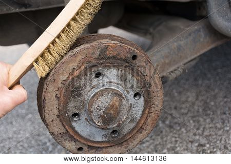 With wire brush rusted brake drum is cleaned