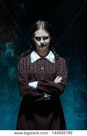 Portrait of a young girl in school uniform as killer woman against school board . The image in the style of Halloween and Addams family