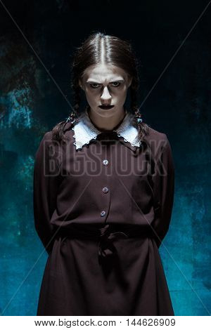 Portrait of a young girl in school uniform as killer woman against school board . The image in the style of Halloween and Addams family