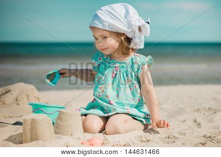 little girl playing with sand on the beach