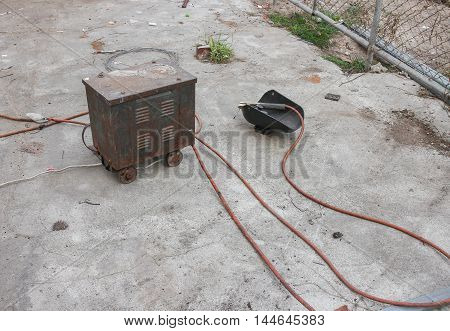 Welding and mask still life equipment  of rod-holder with cable and electrode for electric arc on a cement floor.