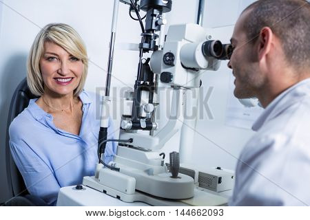 Optometrist examining female patient on slit lamp in ophthalmology clinic